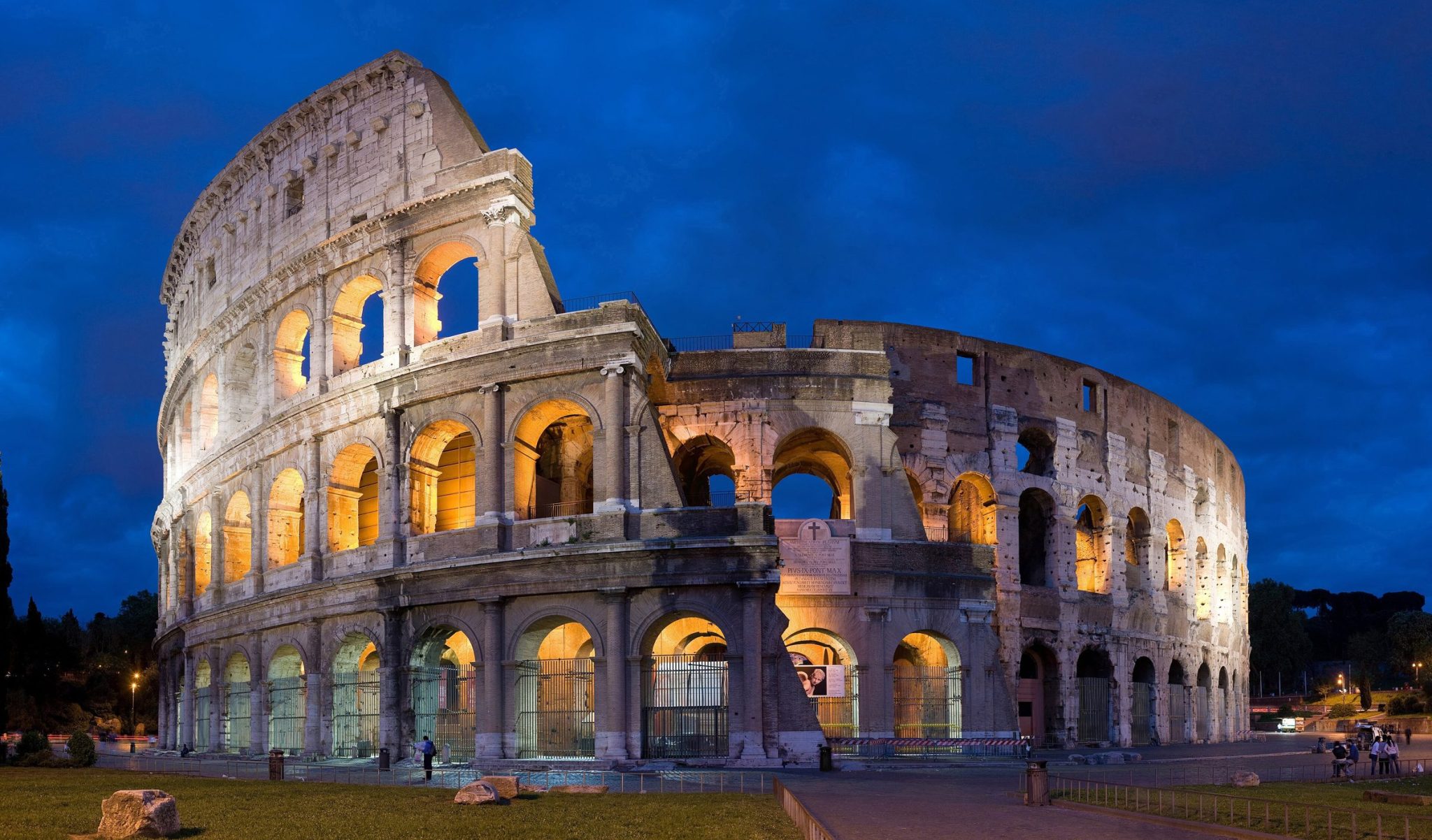 The Colosseum illuminated against a deep blue evening sky
